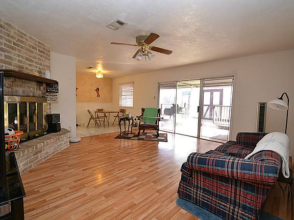 Spacious family room featuring hardwood laminate floors, corner fireplace and a ceiling fan with lig