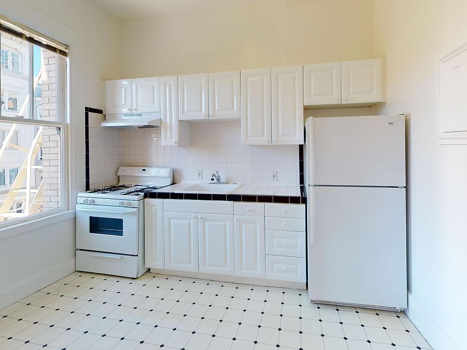 Kitchen with cabinets, gas stove, fridge, tile backsplash, and window