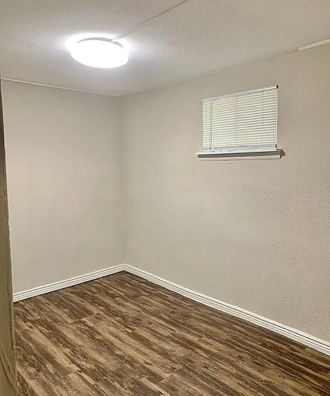 Cozy apartment room with elegant wood flooring and soft neutral walls, illuminated by modern lighting.