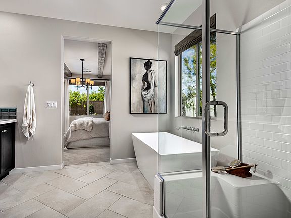 A modern, minimalist bathroom with a white vanity, glass shower enclosure, and a framed artwork on t