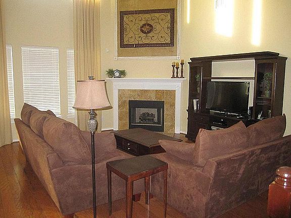 The main living room offers 2-story windows, custom drapes, gas fireplace  and hand-scraped hardwood flooring which carry in from the entry all the way into the kitchen area.