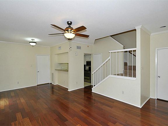The kitchen is at the far end of the living space, beyond the staircase. There is also a half bath j