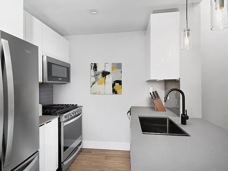 Renovated Package I kitchen with quartz stone countertop, tile backsplash, and stainless steel appliances