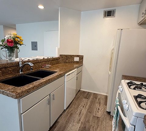 Kitchen has granite counter tops, dishwasher, stove, refrigerator and microwave