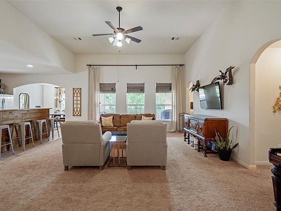Heading into the home is an extremely spacious living room. Custom drapes which emphasize the height of the ceiling will stay. All this space lends itself to many furniture arrangements. This shot shows the hall to one of the secondary bedrooms to th