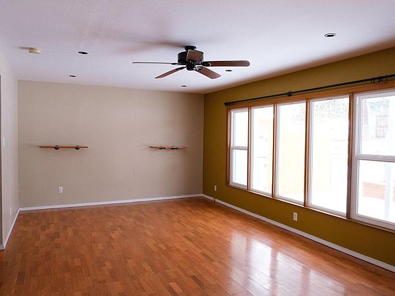 The living room has recessed lighting and a ceiling fan with large windows and a door leading to a patio in the backyard. The space is large enough for a dining table off the kitchen or it can be enjoyed as a large living space.