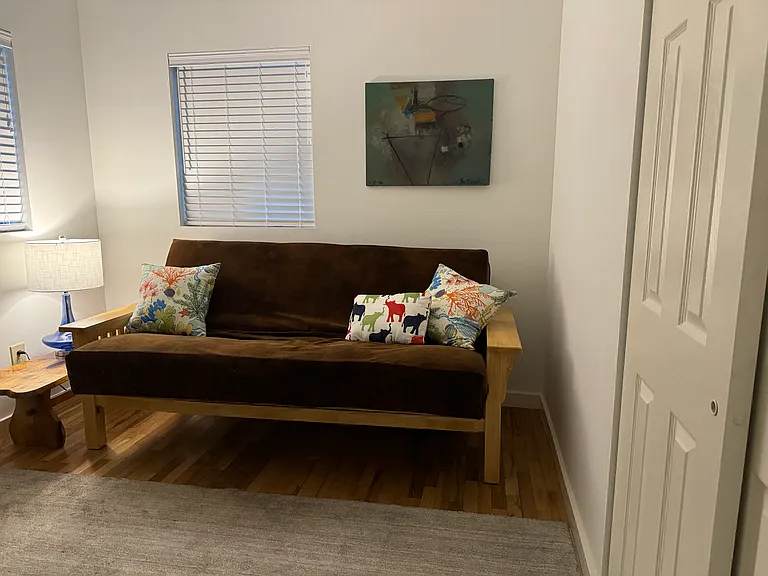 Second bedroom or office area. Table and lamp for computer, futon couch bed, wool rug, and additional seating.