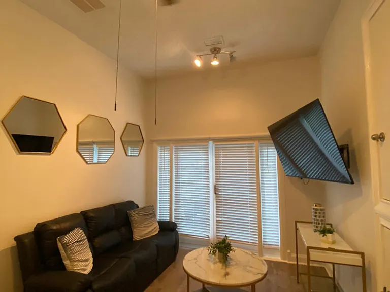 Living area features a 2-seat sofa, decorative mirrors, coffee table, and Smart TV.