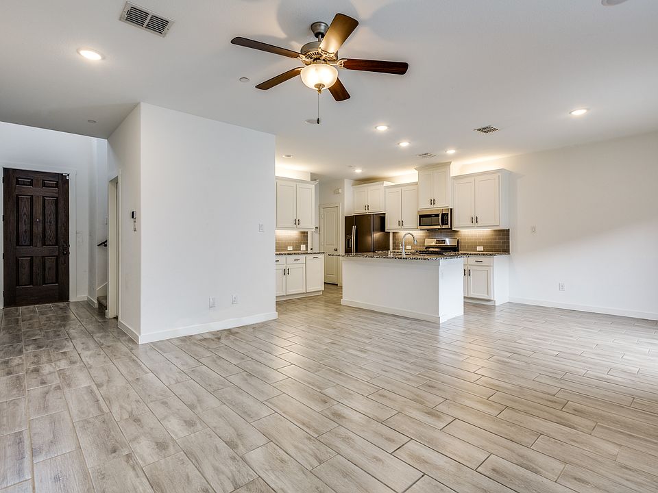 View from the living area with dining area on the right and large kitchen with island, gas range, refrigerator, walk-in pantry, and extra cabinets, and extra granite countertops.