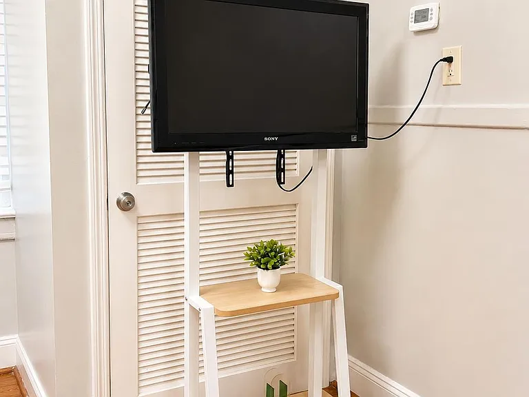 Nook with hardwood floors and a movable TV stand, offering a convenient media setup near interior storage.