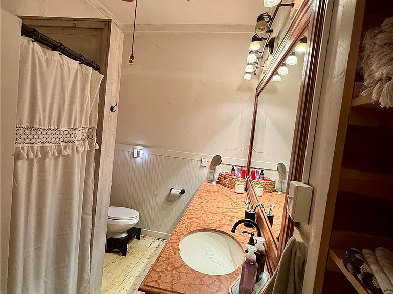 Bathroom featuring a wood-finish vanity with an integrated sink and a large mirror with track lighting