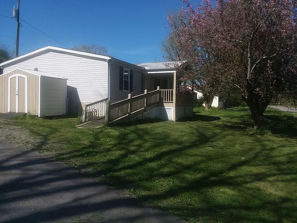 Front view of the house showing the covered deck, ramp,and storage shed.