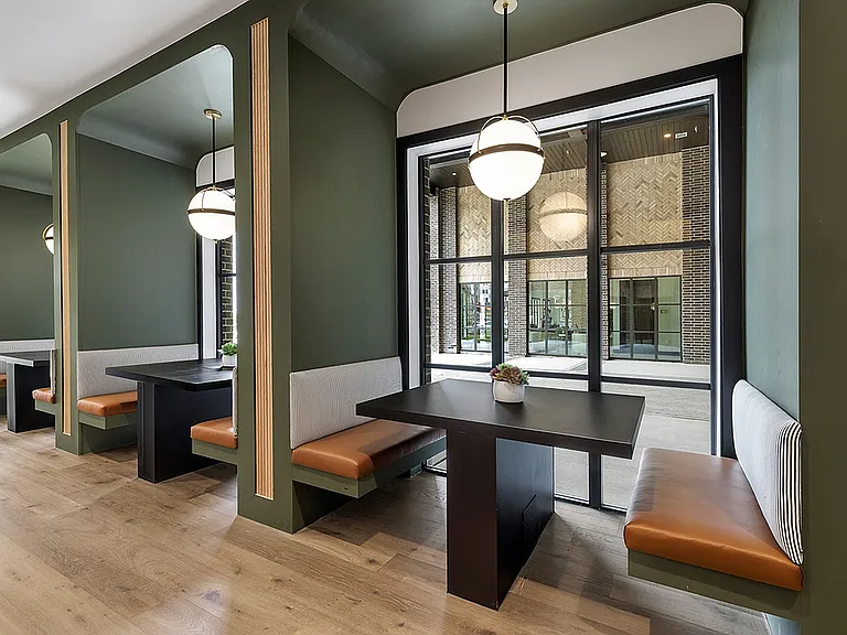 Modern seating alcove with elegant green walls, sleek black tables