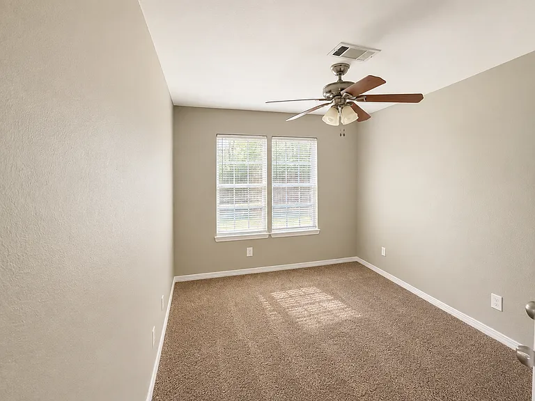 Garden Suite _ A cozy and inviting bedroom featuring soft carpeting, abundant natural light, a ceiling fan, and a peaceful atmosphere. Conveniently located near the shared kitchen and just steps from its dedicated private bathroom.