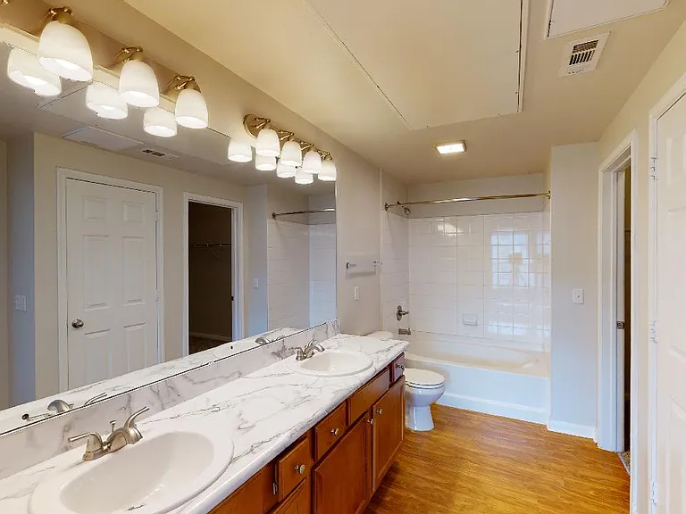 Apartment bathroom with wood-style flooring and double sinks.