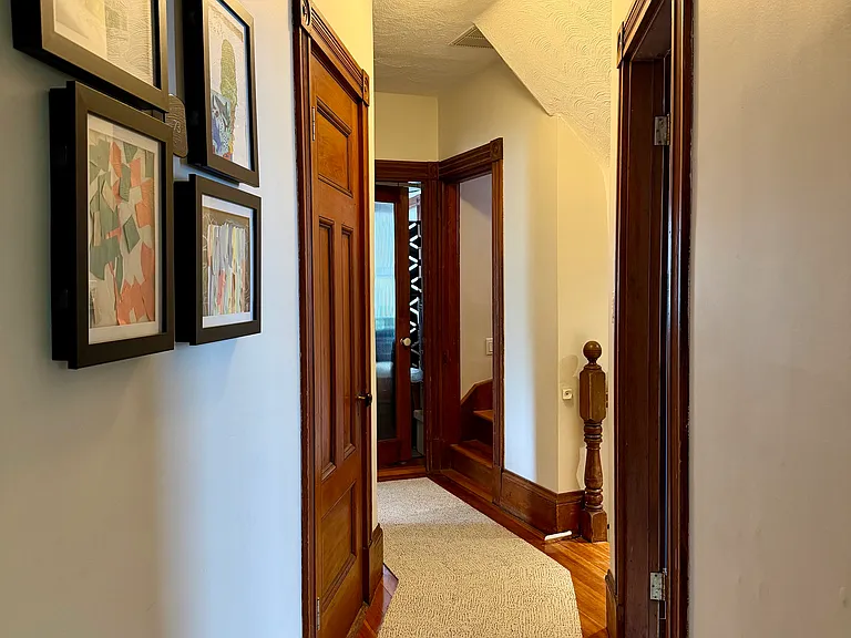 Main floor hallway looking toward front entry stairs, powder room and office at the end of hall.