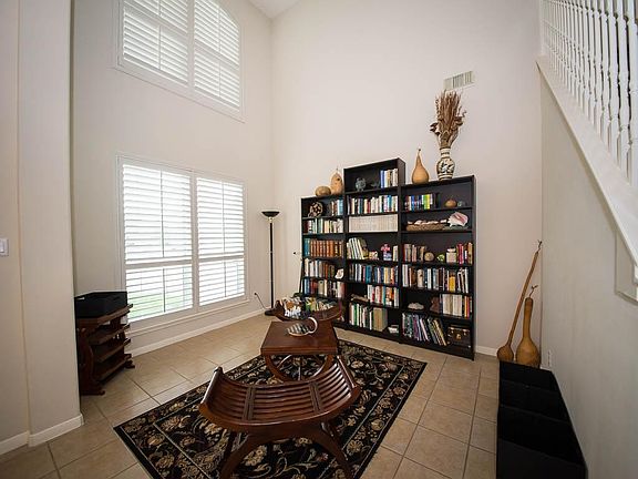 High ceilings makes this library/living room a welcoming entrance. Custom Plantation Shutters let gr