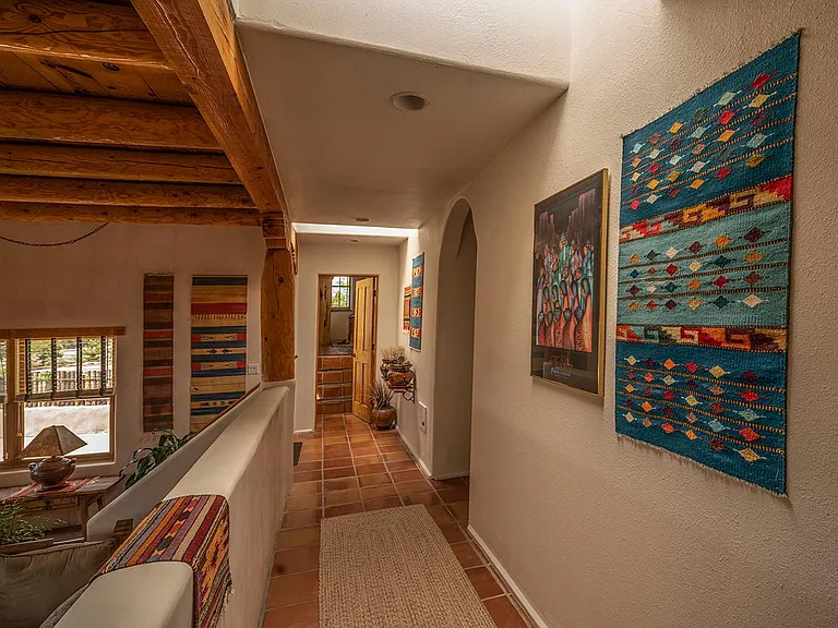 Elevated hallway over living room with 12 ft beam and viga ceiling.
