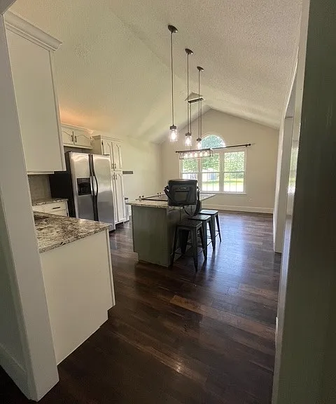 Kitchen with vaulted ceilings, kitchen island, granite countertops and tiled backsplash.