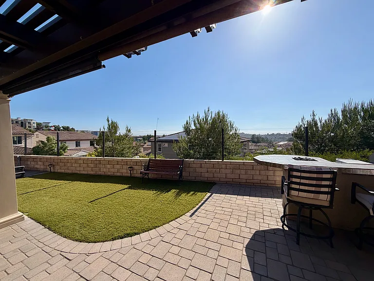 West-facing backyard with built-in grill, built-in pergola, and turfed lawn
