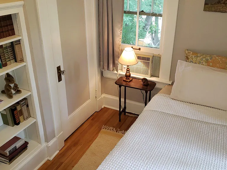 Cozy small bedroom with twin bed, built in bookcase and french casement windows.