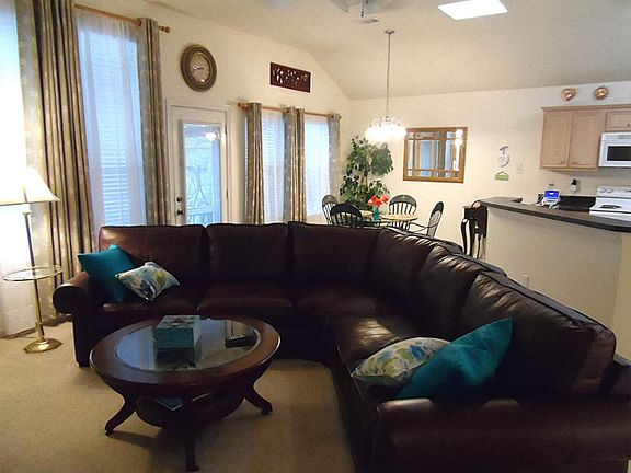 Open living, kitchen and breakfast area with a high ceiling.