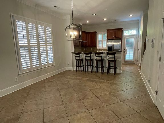 This view shows the dining area with the hanging light fixture, recessed lighting, and kitchen with a breakfast bar