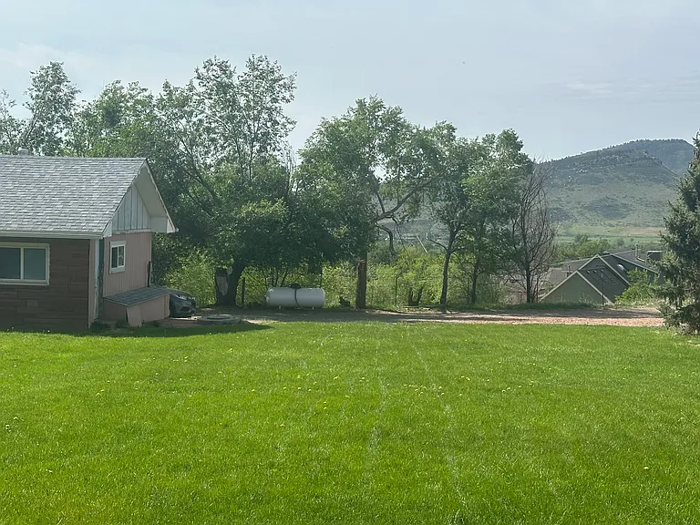 Large grassy yard with view of historic scale house and local mountains