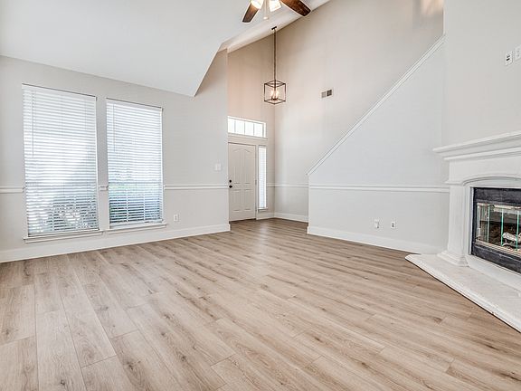 Spacious living room featuring arched walkways, light oak floors, high ceilings, and a beautiful fireplace