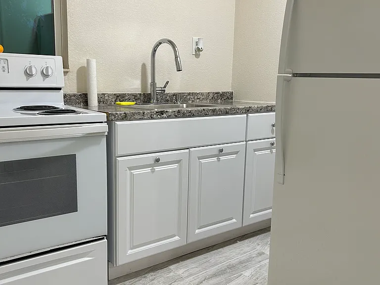 Bright kitchen with full-size refrigerator, stove, sink, and cabinet storage.