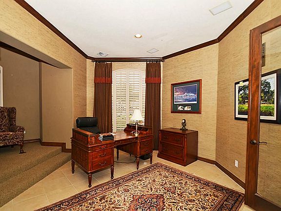 The gentleman's study sits on two levels and is enhanced by plantation shutters and grass cloth walls.