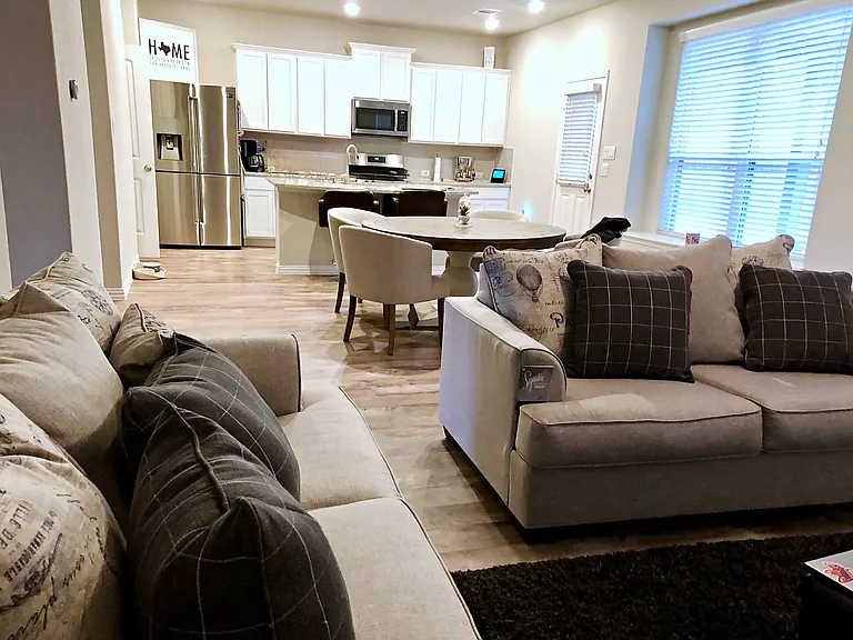 Open-concept living and kitchen with a cozy sectional, dining nook, and stainless appliances.