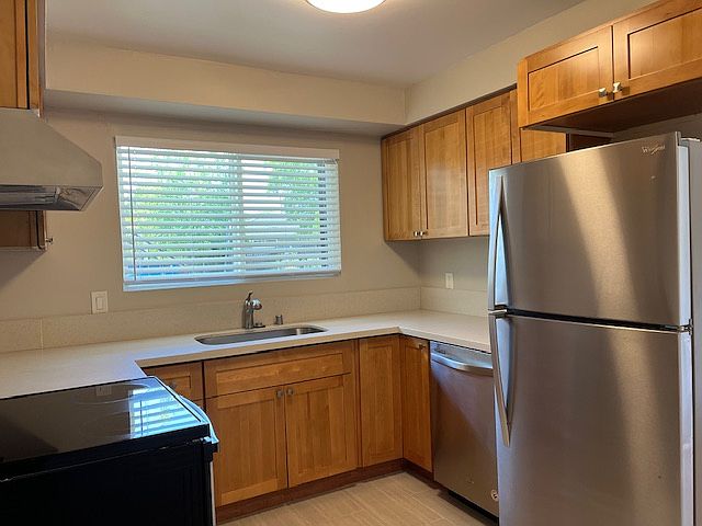 Beautiful kitchen has natural maple shaker cabinets with white quartz counter tops, stainless steel appliances including refrigerator, dishwasher and electric stove and range hood. Kitchen has tile flooring, LED lighting in additional to natural light.