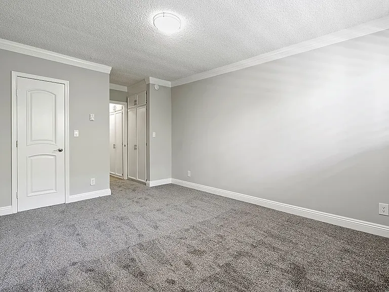 Carpeted bedroom with crown moulding and private bathroom.