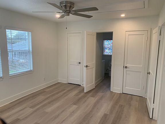 View of bathroom (open door) and closets (closed doors), from corner of bedroom