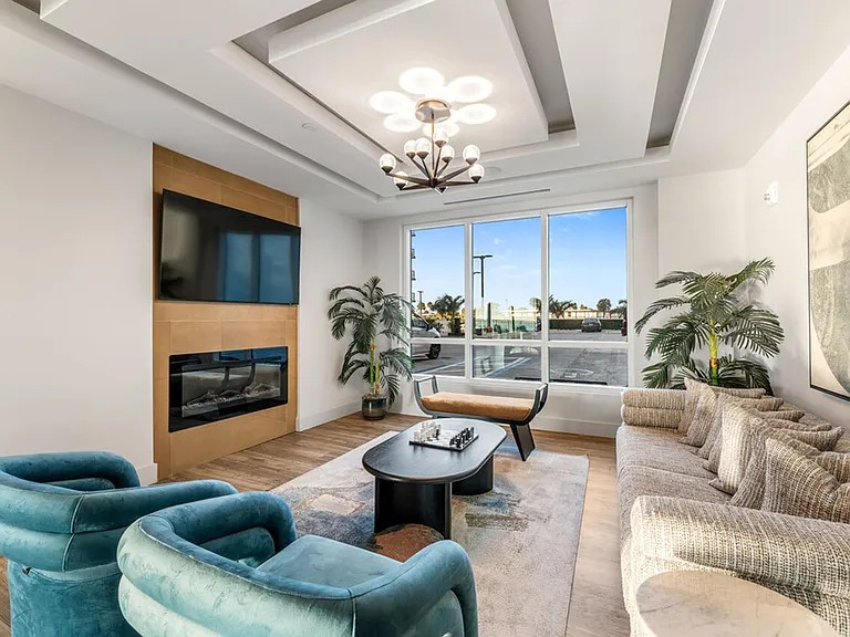 Elegant living room with modern decor, featuring plush armchairs, a contemporary sofa, a sleek fireplace, and large windows.
