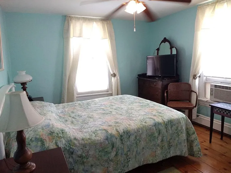 Bedroom with queen bed and original wood floors. (Note: window without A/C overlooks 2nd floor porch.)
