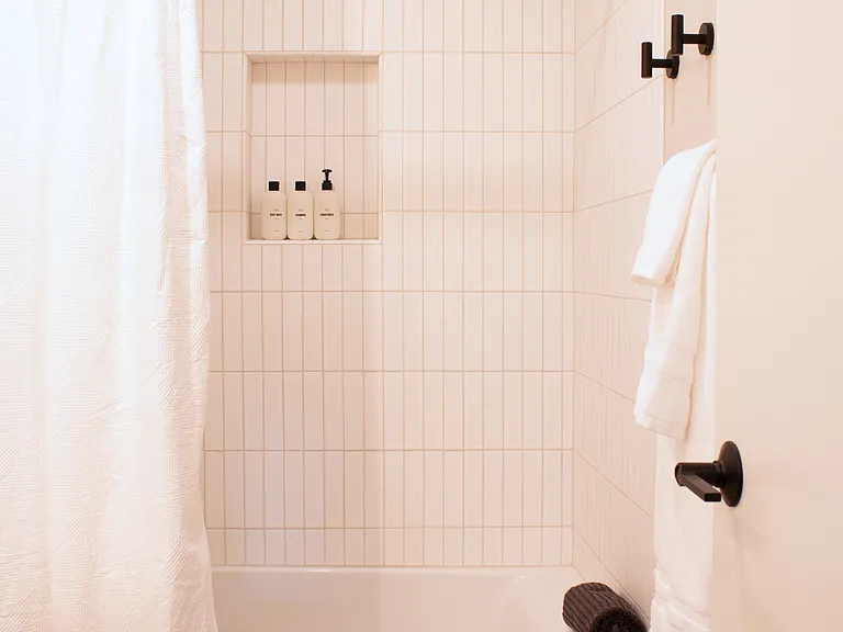 Light-filled bath with tub/shower combo, clean tile, and built-in niche