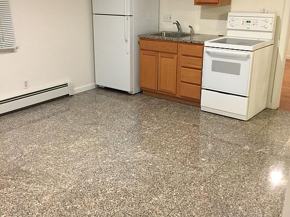 Kitchenette, tiled floors, electric stove, AC unit on wall. This room serves both as a kitchen/dining/living room