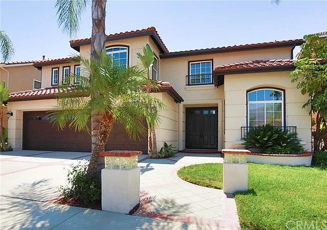 Front of home showing custom landscape and hardscape as well as three car garage and new exterior pa