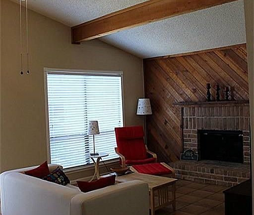 Nicely-sized Living Room w/cozy brick fireplace & high beamed ceiling.
