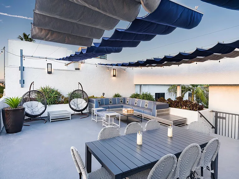 Lounge in the open air with shaded seating, dining area, and cozy gathering spaces under string lights.
