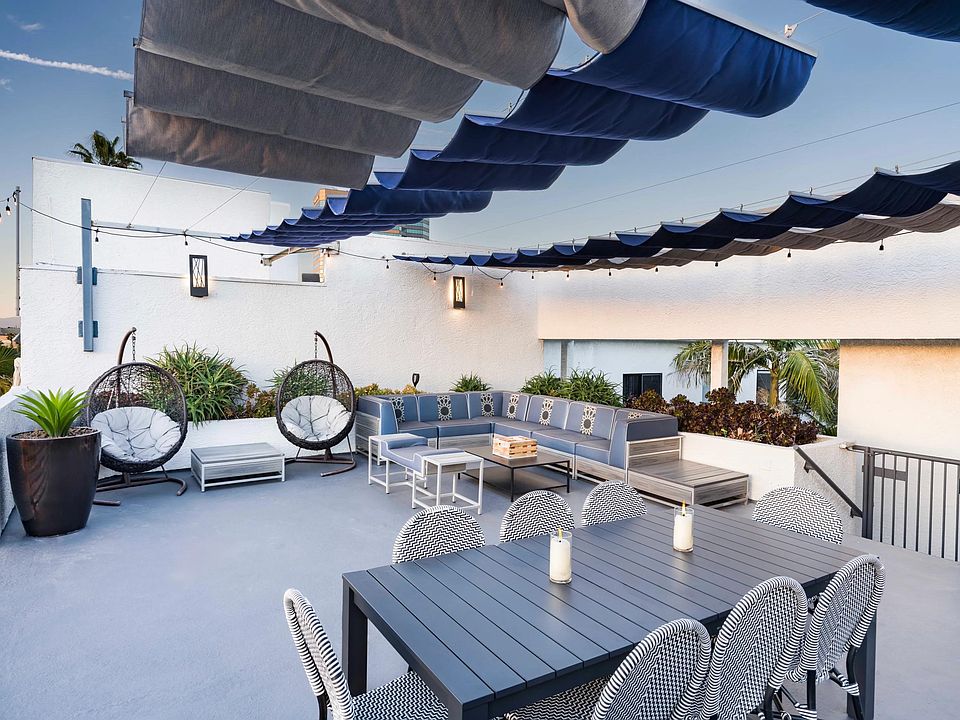 Lounge in the open air with shaded seating, dining area, and cozy gathering spaces under string lights.