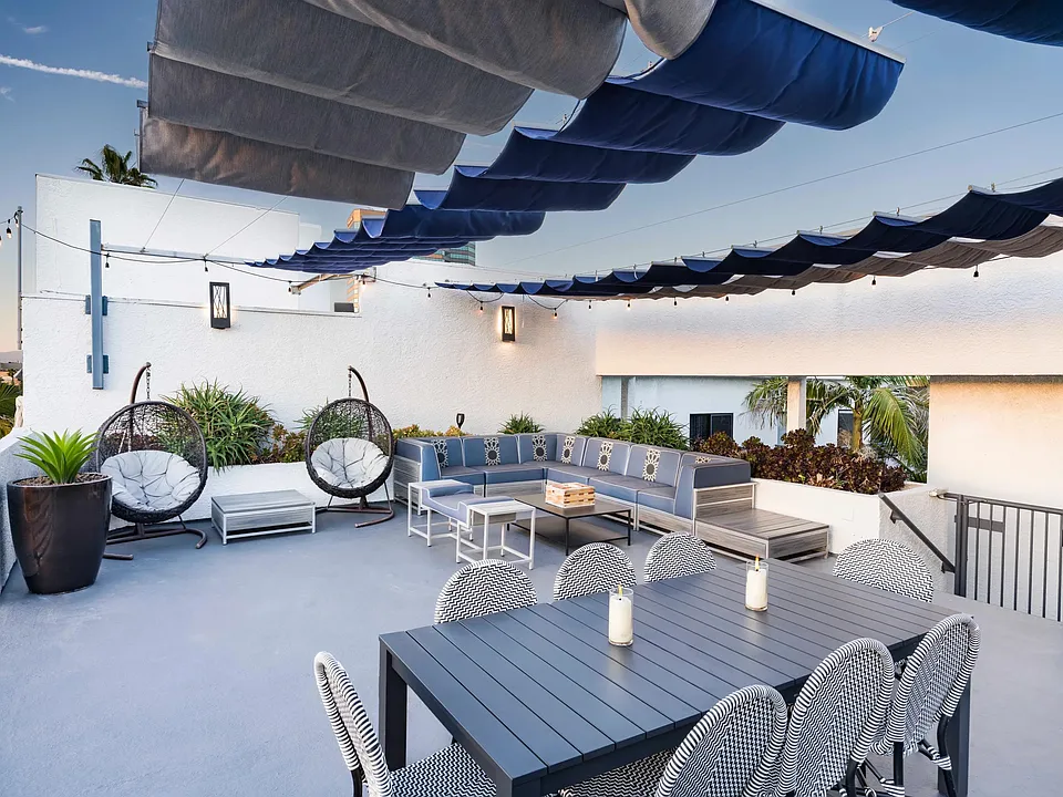 Lounge in the open air with shaded seating, dining area, and cozy gathering spaces under string lights.