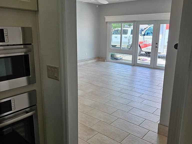 Living room. Converted garage, with porcelain tile, wood shutter windows, ceiling fav, and remote control blinds for the double glass doors and windows.