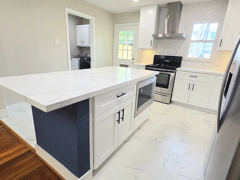 Massive modern island with sleek white cabinetry and a built-in microwave. Bright and airy, great for grab quick meals.