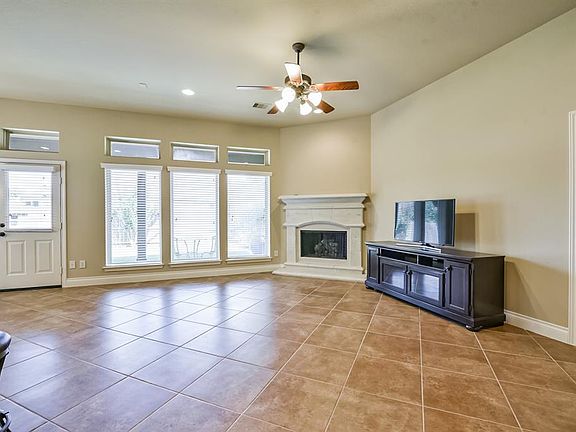 The spacious living room has tile floors, recessed lighting, a ceiling fan and a gaslog fireplace.