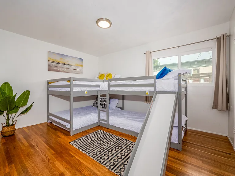 Hardwood floors, a cozy rug, and natural greenery create a warm, inviting atmosphere. Wake up to sunlight streaming through the windows, and enjoy a space that feels like a getaway within your getaway. Perfect for creating unforgettable memories!