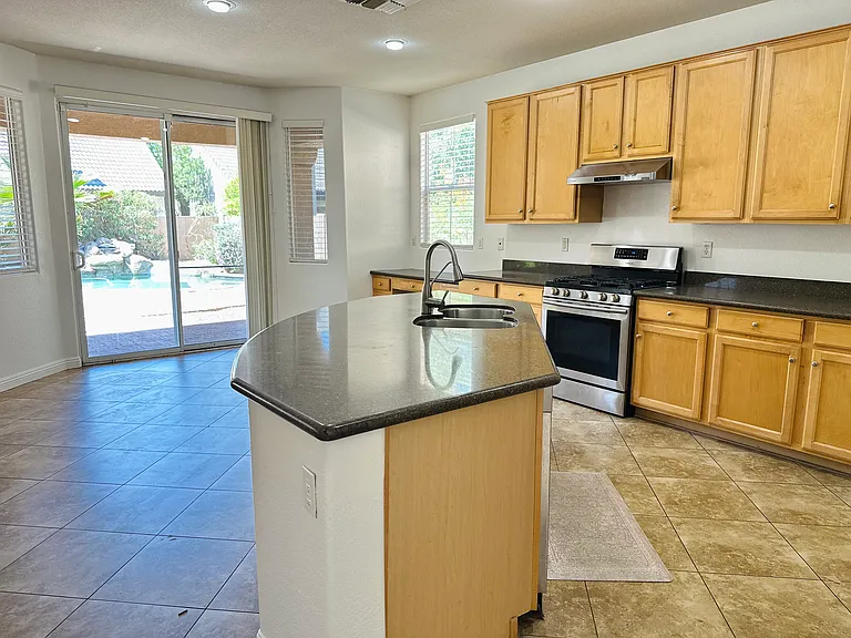 Spacious kitchen with maple cabinets, granite countertops, a center island, and direct access to the private pool and patio.