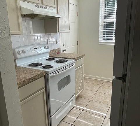 Stove in kitchen with newly painted cabinets.